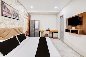 Et hotelværelse med seng, skrivebord, fjernsyn og spejl.