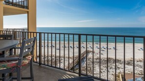 A balcony with a view of a beach, a table, and chairs. - Phoenix Ii 2081 3 Bedroom Condo (Orange Beach)