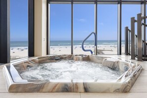 A hot tub with a marble design, located in a room with large windows overlooking a beach. - Phoenix Ii 2153 3 Bedroom Condo (Orange Beach)