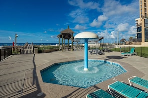 A rooftop pool area with a water feature, lounge chairs, and a view of the ocean. - Phoenix Ii 2141 3 Bedroom Condo (Orange Beach)
