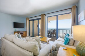 A hotel room with a balcony, a sofa, a table, and a TV. - Phoenix Ii 2141 3 Bedroom Condo (Orange Beach)