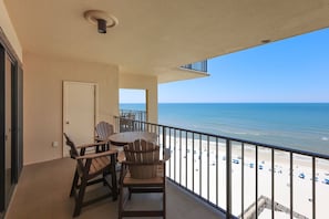 Ein Balkon mit Blick auf den Strand, einem Tisch und Stühlen.