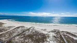 A beach with a wooden boardwalk leading to the shore, sandy beach, and clear blue water. - Phoenix East 1408 1 Bedroom Condo (Orange Beach)