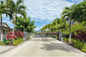 A gated entrance with a paved walkway leading to a residential area with houses and lush greenery. - Na Hale O Keauhou#N6: Beautiful Corner Townhome with Ac! (Kailua Kona)