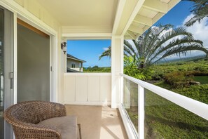 A balcony with a wicker chair, a view of a house, and a landscape with palm trees. - Na Hale O Keauhou#N6: Beautiful Corner Townhome with Ac! (Kailua Kona)