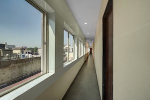 A corridor with large windows, a tiled floor, and a view of buildings outside.