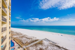 A beachfront hotel with a pool, a sandy beach, and a clear blue sky. - Phoenix Ii 2098 3 Bedroom Condo (Orange Beach)