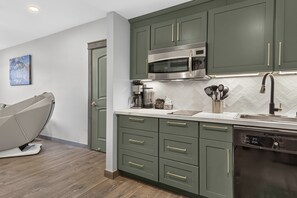 A modern kitchen with green cabinets, a stainless steel microwave, and a built-in dishwasher. - Premium Unit 4573 -1br Kitchenette Founders Pointe 1 Bedroom Condo (Winter Park)