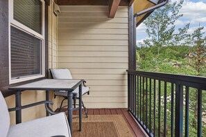 A covered outdoor area with a table and chairs, a wooden floor, and a view of a residential area with trees and houses. - Premium Unit 4573 -1br Kitchenette Founders Pointe 1 Bedroom Condo (Winter Park)