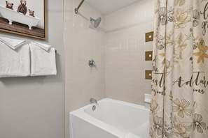 A bathroom with a bathtub, a shower, and a toilet. There are two white towels hanging on a rack. - Premium Unit 4571 - Studio - Founders Pointe Condo (Winter Park)