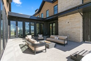 A modern outdoor living area with a sofa set, a fire pit, and a stone wall. - 4br Deer Valley Home With Hot Tub, Sauna & Views 4 Bedroom Home (Heber City)