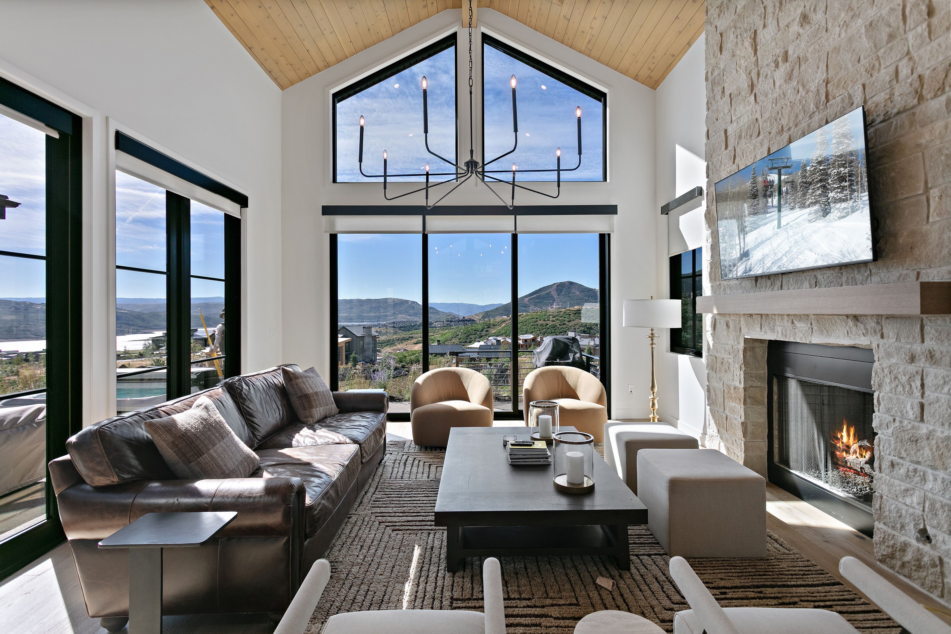 A spacious living room with a large window, a fireplace, and a view of the mountains.