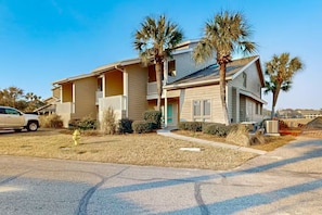 A two-story building with a balcony on the second floor, a fire hydrant in the front yard, and palm trees. - Beach House On The Lake 232 3 Bedroom Condo (Miramar Beach)