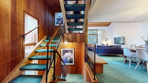 A wooden staircase with blue carpeted steps leading to a lower level. - Meadow Ridge #8 3 Bedroom Condo (Mammoth Lakes)