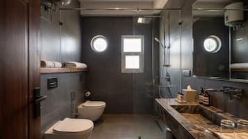 Een moderne badkamer met toilet, bidet en douche. Er is een wastafel met spiegel en wastafelbak.