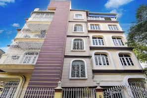 A multi-story building with balconies, a central vertical structure, and a gated entrance. - Super Collection O Jyotirindra Nandi (Kolkata)