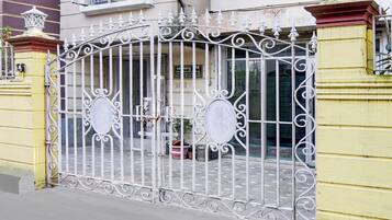 A gated entrance with ornate metalwork, a sign indicating a business or office, and a potted plant.
