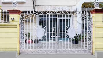 A gated entrance with a metal gate featuring decorative scrollwork and two circular signs.