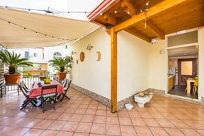 An outdoor patio with a wooden pergola, tiled floor, and potted plants. - Terrazza Lulu by Napoliapartments (Naples)