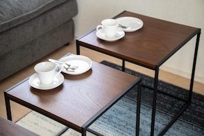 Two small wooden tables with white cups and saucers, and cutlery on them. - Hotel HIRAKU RYUKYU (nahashi)