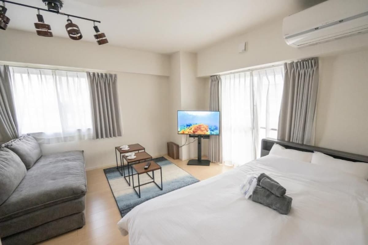 A hotel room with a bed, a sofa, a TV, and a small table.