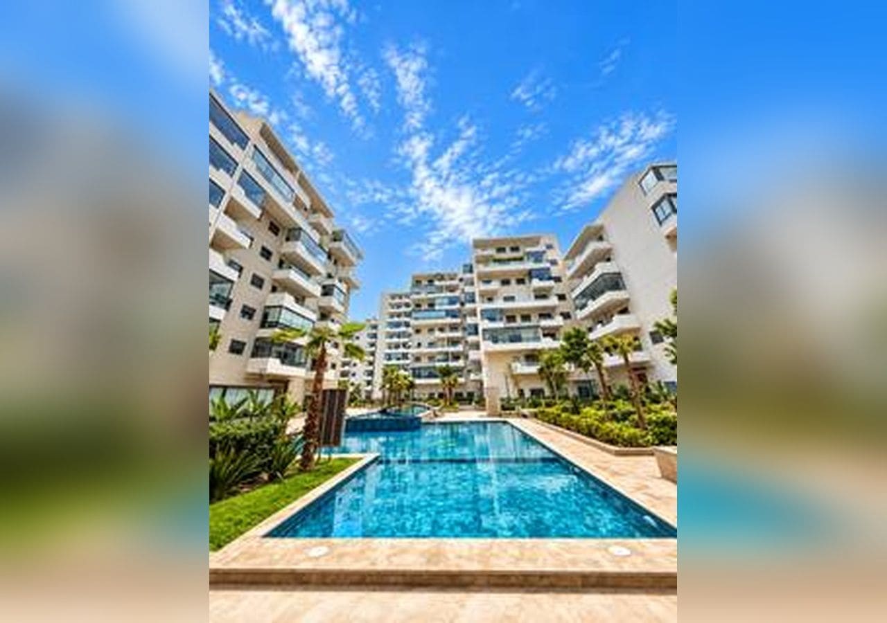 A residential complex with multiple high-rise buildings, a swimming pool, and landscaped areas.