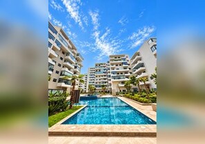 Un complexe résidentiel comprenant plusieurs immeubles de grande hauteur, une piscine et des espaces paysagers.
