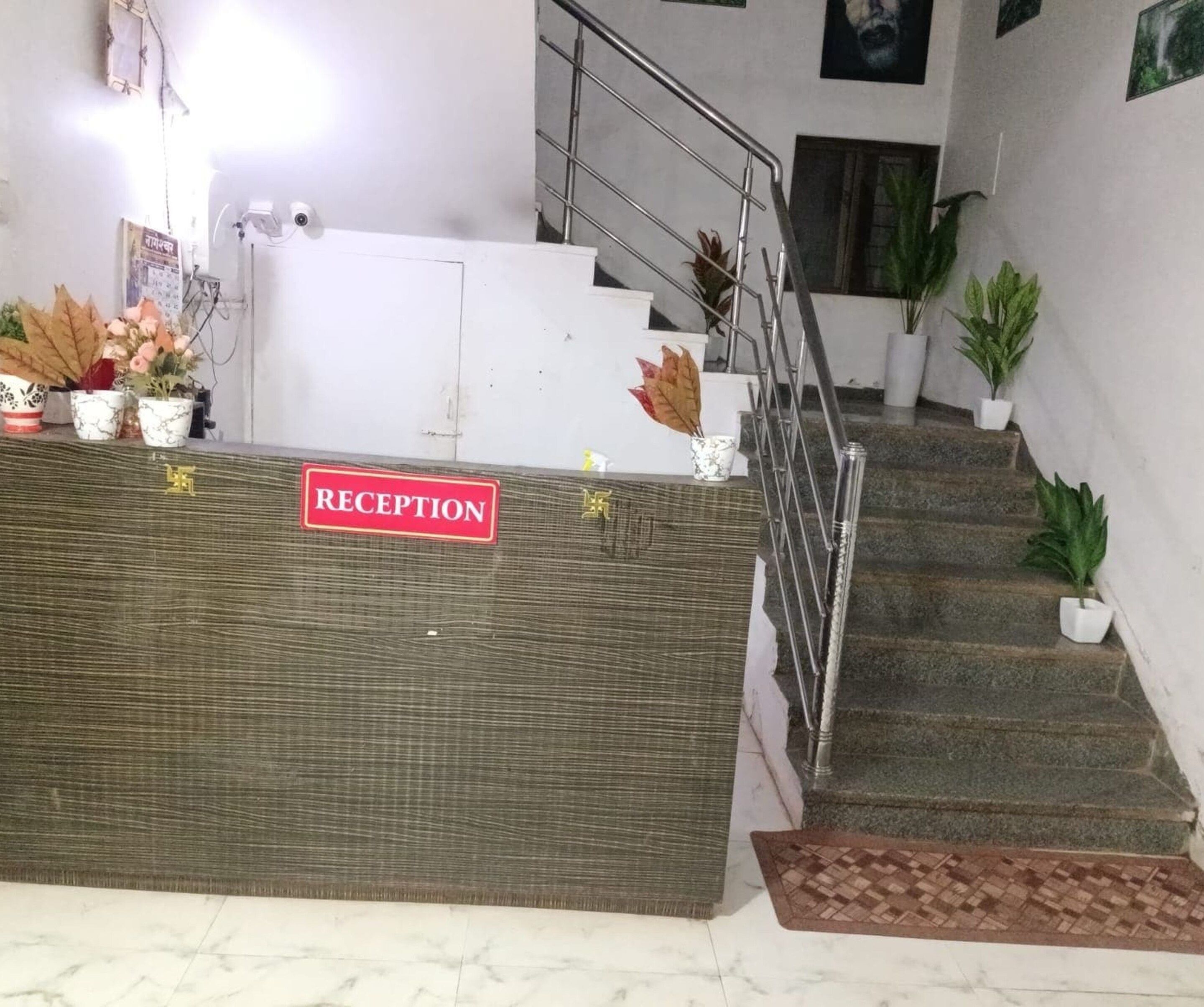 A reception desk with a 'RECEPTION' sign, a staircase, and potted plants.
