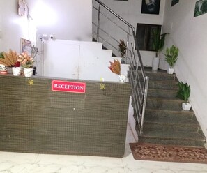 A reception desk with a 'RECEPTION' sign, a staircase, and potted plants. - Deluxe With Balcony Oraa Stay (Mahabaleshwar)