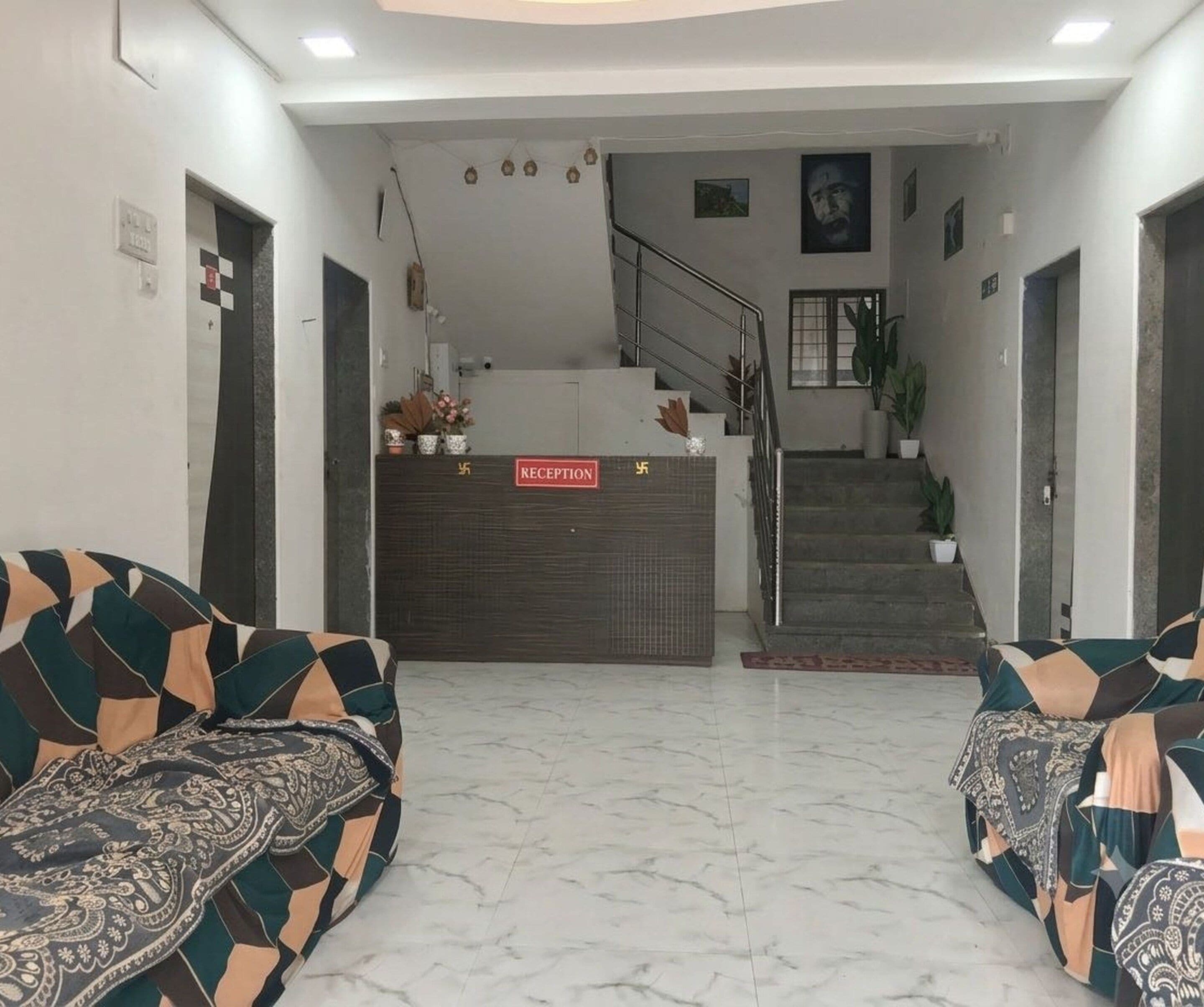 A reception area with a reception desk, a staircase, and two patterned sofas.