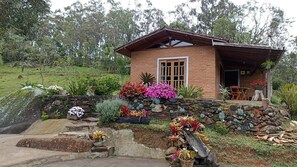 A rustic house with a stone foundation, a wooden porch, and a variety of potted plants and flowers.