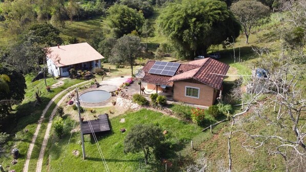 A house with a solar panel roof, a swimming pool, and a garden.
