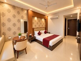 A hotel room with a bed, bedside table, chair, and a small table with a plant.