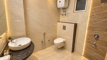Un baño moderno con suelo de mármol, un lavabo, un inodoro y una zona de ducha.