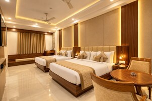 A hotel room with two beds, a sitting area with a table and chairs, a ceiling fan, and recessed lighting.