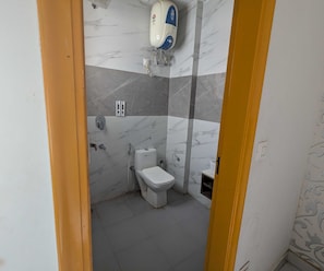 Un baño con inodoro, bidé y calentador de agua instalado en la pared.