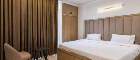 Un dormitorio moderno con una cama grande, una silla, una mesita y un armario.