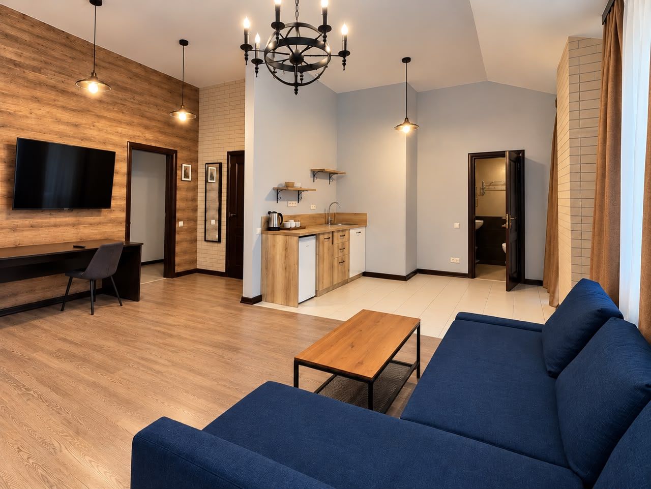 A modern living room with a blue sofa, a wooden coffee table, and a TV mounted on a wooden wall.