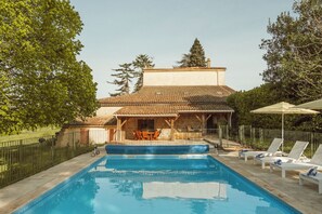 A swimming pool with a patio area, lounge chairs, and a building with a tiled roof. - Gorgeous Family-Friendly Villa in Southwest France - Sleeps up to 10 (Mauvezin-sur-Gupie)