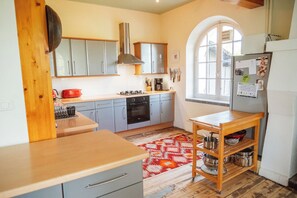 A kitchen with grey cabinets, a wooden countertop, a red rug, and a window with a view. - Gorgeous Family-Friendly Villa in Southwest France - Sleeps up to 10 (Mauvezin-sur-Gupie)