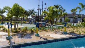 A pool area with a slide, water features, and palm trees. - Near Disney 5BR Pool Home with Themed Kids Rooms (Kissimmee)