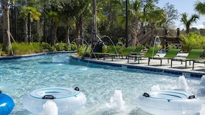 Una piscina con flotadores, sillas de descanso y un entorno tropical con palmeras.