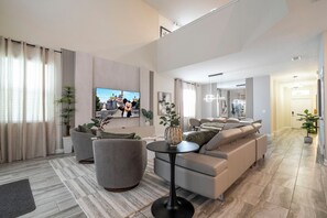 Un salon moderne comprenant un canapé, des fauteuils, une table basse et un téléviseur.