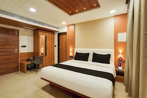A modern bedroom with a large bed, a desk, and a chair.