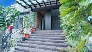 Una escalera conduce a la entrada de un edificio, con macetas a cada lado.