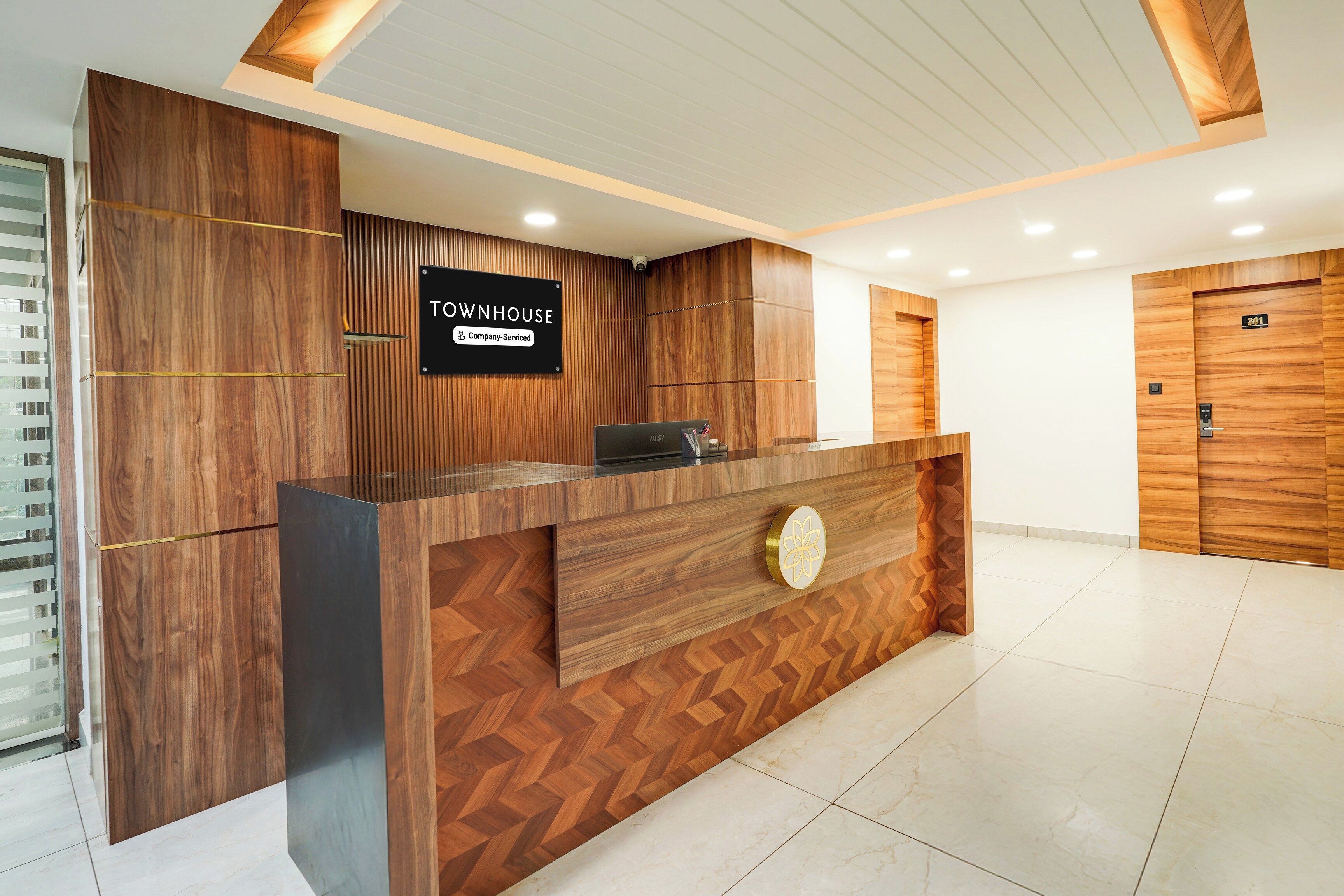 Un mostrador de recepción con un letrero que dice 'TOWNHOUSE', una etiqueta de servicio de la empresa y una cámara de seguridad encima.