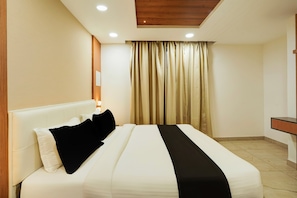 A hotel room with a bed, curtains, a nightstand, and a wooden ceiling. - Townhouse IIM Bangalore (Bangalore)
