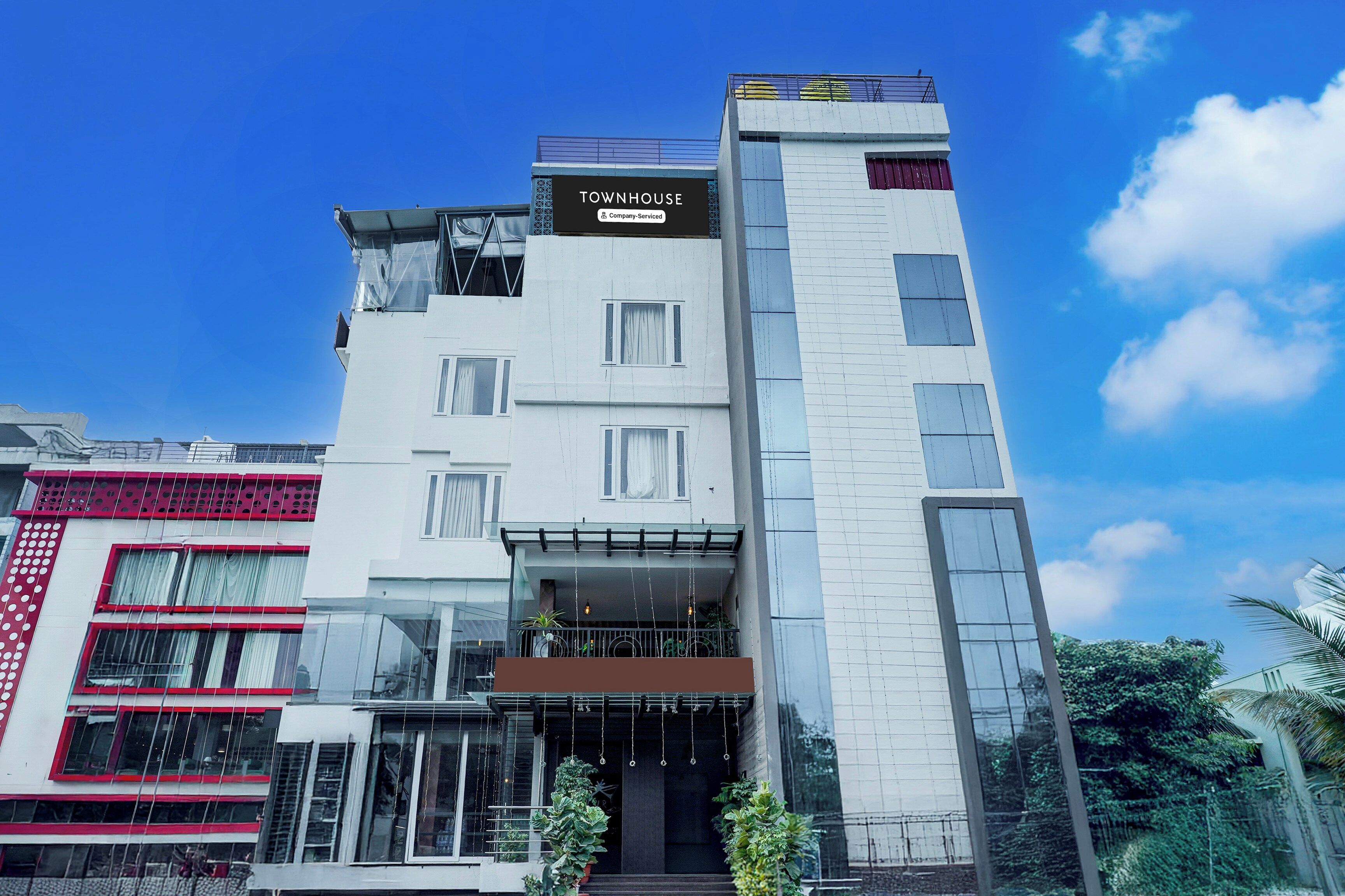 Un edificio de varios pisos con un cartel que dice 'TOWNHOUSE' y 'Company Serviced'.