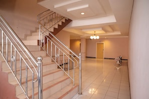 A spacious interior with a staircase, a chandelier, and a bench.