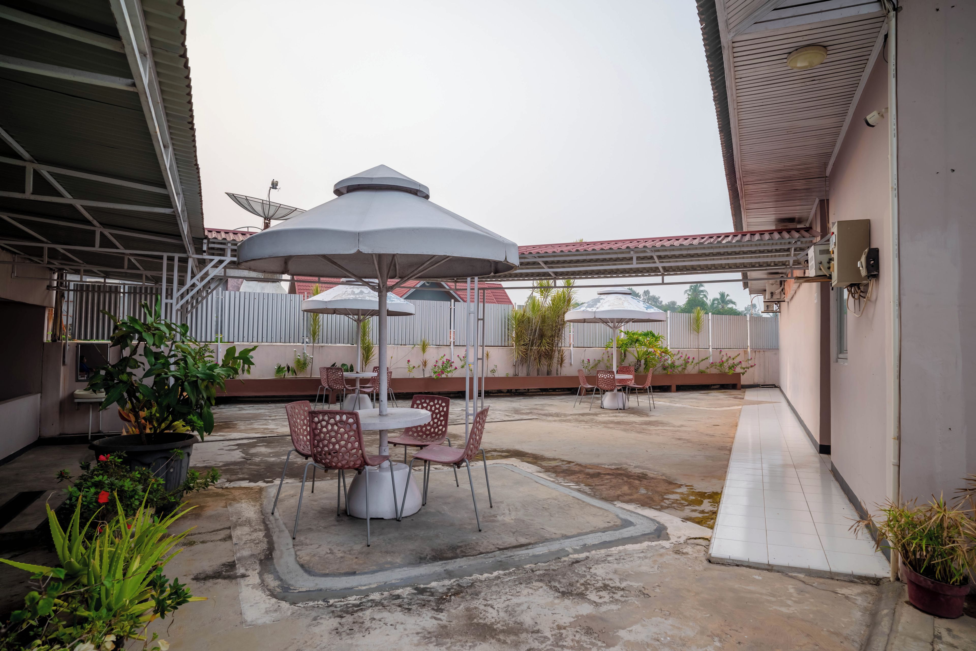 An outdoor patio area with tables and chairs, umbrellas, and potted plants.